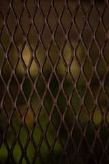 Abstract texture of old stainless steel rusted metal fence. Wire mesh. Square iron rivets on the door grill. The cage metal net on nature background for designer use.