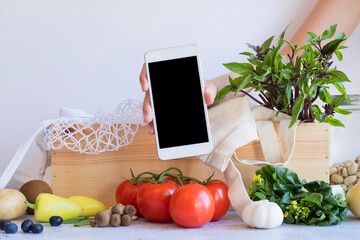 mobile phone with fresh vegetable in the wood box. online grocery and organic farmer product shopping application. food and cooking recipe or nutrition counting.flat lay.