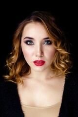 Fototapeta premium Portrait of gorgeous young woman on dark background. Sensual young woman with red lips and bright makeup. Beautiful healthy face of the young pretty woman with fresh skin.
