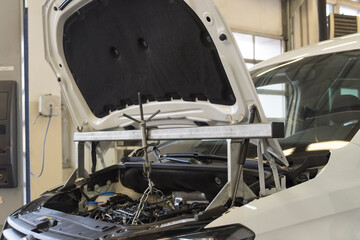 Car repair at a service station. A special tool is installed on the car for repair. The engine compartment of the car.