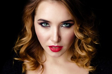 Fototapeta premium Portrait of gorgeous young woman on dark background. Sensual young woman with red lips and bright makeup. Beautiful healthy face of the young pretty woman with fresh skin.