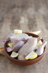 raw coquelet chickens prepared for roasting with vegetables and herbs