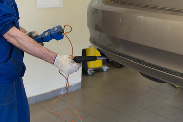 Car repair at a service station. A professional mechanic measures the exhaust of a car. Car exhaust...