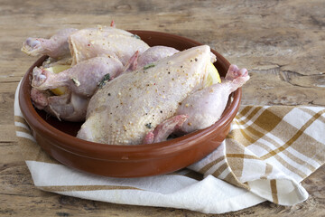 raw coquelet chickens prepared for roasting with vegetables and herbs