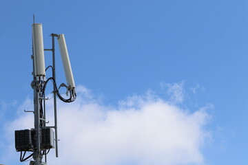 Cellular, mobile phone transmitter tower with blue sky and clouds middle