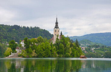 Fototapeta na wymiar Beautiful morning at Lake Bled and Julian Alps in the background. The lake island and charming little church dedicated to the Assumption of Mary are famous tourist attraction in Slovenia