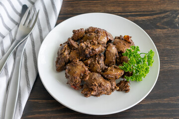 Fried Chicken Livers: A plate of chicken livers fried with tomato and spices and garnished with a sprig of parsley