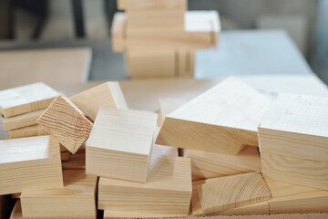 Pile of wooden bricks lying on workbench in large workshop of furniture factory