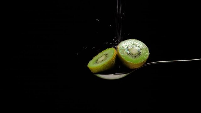 dos mitades de kiwi cortado cayendo slow motion az&uacute;car blanca