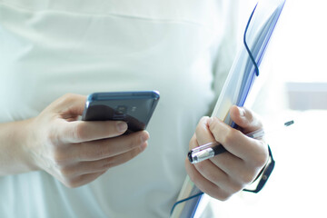 Frau hält blaue Datei, Stift und Handy in der Hand