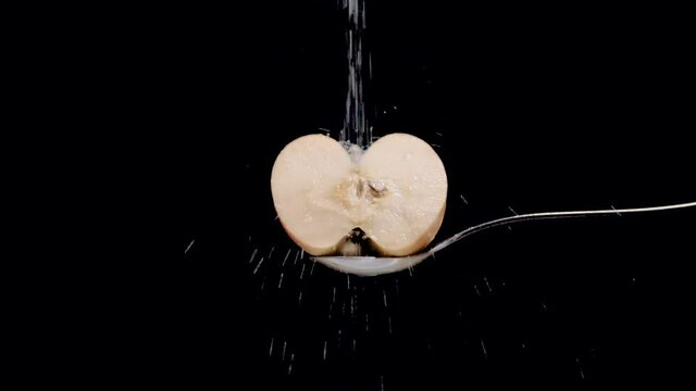 Manzana blanca cortada por la mitad cay&eacute;ndole az&uacute;car  en c&aacute;mara lenta