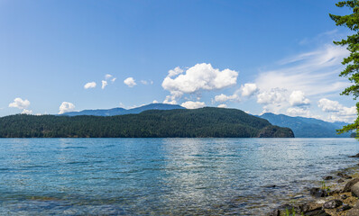 veiw from the shore to Harrison Lake british columbia Canada green land blue water and sky.
