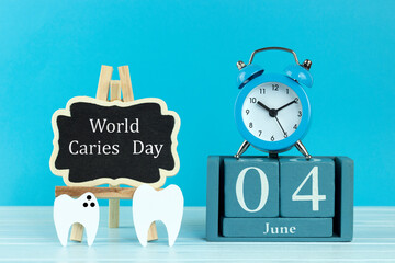 wooden calendar with the date of June 4, easel, tooth with caries on a blue background, place for text, World Caries Day