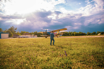 The boy is running across the field, in the background is an old plane