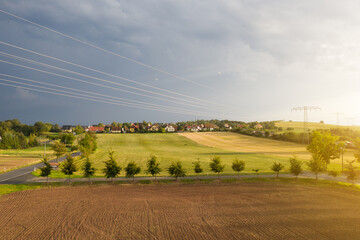 Luftaufnahme eines kleinen Dorfes mit Feld und Stromleitung im Vordergrund