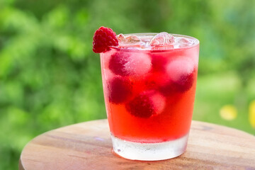 Detox water with raspberry and ice on a green background