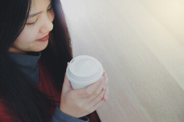 Beautiful asian woman enjoys drinking a cup of hot coffee during winter time. White plain background, space for text.