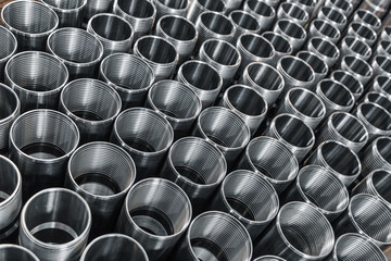 Closeup pattern of shiny circular precision stainless steel industrial machine parts arranged in rows. Steel products to automotive industry. Billet obtained on lathe from steel and cast iron