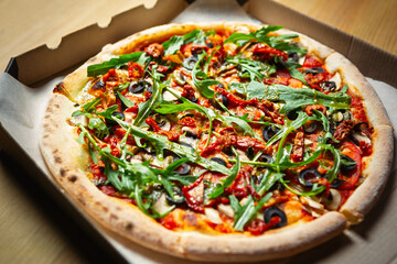 Delicious fast food delivery.Italian pizza with arugula,black olives,dried tomatoes,white...