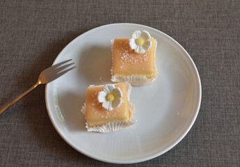 Pie Petit four with sugar flower and coconut shavings on a white saucer.