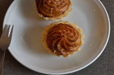 Cake basket with marzipan and marmalade on a white saucer. Baked dough. Makronen tartlets.