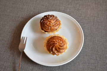Cake basket with marzipan and marmalade on a white saucer. Baked dough. Makronen tartlets.