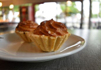 Cake basket with marzipan and marmalade on a white saucer. Baked dough. Makronen tartlets.