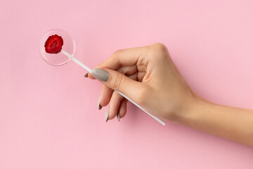 Womans hand holding lollipop made from natural dehydrated berries on pink