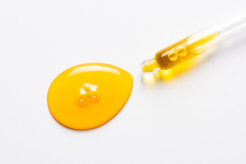 Cosmetic dropper with yellow oil. Anti-aging serum on white.