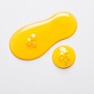 Cosmetic oil on white. Yellow drops close up.