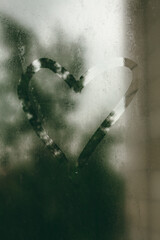 Painted heart on a foggy window. Cloudy and rainy weather.
