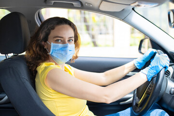 Young woman in a mask sitting in a car