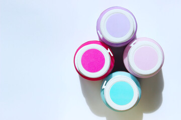 Blurry image of four cans of paint on light blue background, horizontal view. Space for text....