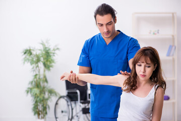 Fototapeta premium Injured woman visiting young male doctor osteopath