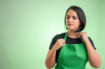 Female cook with green apron and black t-shirt arranges her apron