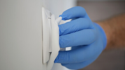 Man Wearing Protection Gloves Cleaning and Disinfecting Light Switch from the Office Room Using Disinfectant Against Covid-19  Viruses