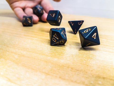 A hand tossing a string of blue dice onto a wooden surface
