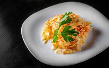 fresh vegetables salad with cabbage and carrot in a white plate on dark wooden table