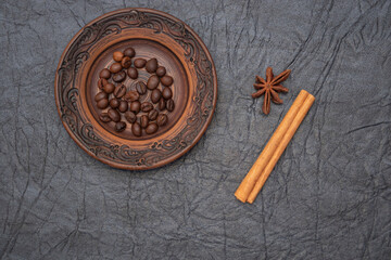 Homemade saucer made of glazed clay. A pinch of brown roasted aromatic coffee beans.