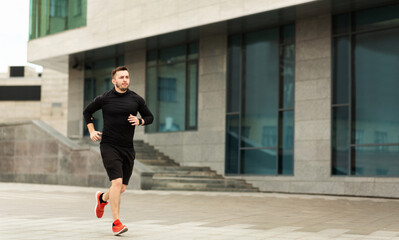 Sporty young man running in city center in the morning