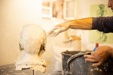 Ein Mann macht einen Abgruss aus Gips eines Tonportraits