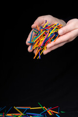 Hand letting coloured wooden  sticks drop on black