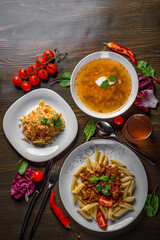 three-course set on a table. Tasty lunch set made of three meals, such as soup,  salad and pasta penne bolognese