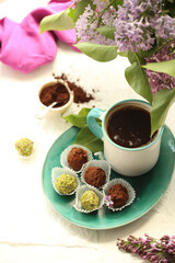 A plate with chocolates, a cup of tea and a bouquet of lilac flowers.
