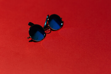 Close-up of round glasses on red background.