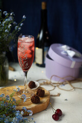 Festive table, a glass of pink champagne, truffle candies, a bottle of wine and a gift. Beautiful photo.
