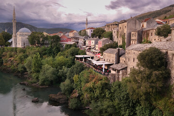 Fototapeta na wymiar Panorama miasteczka Mostar w Bośni i Hercegowinie nad rzeką Neretwą wraz z meczetami, wzgórzami i kamiennymi domami