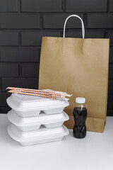 Takeaway concept. Food box with sushi and rolls, soy sauce, chopsticks and paper bag.