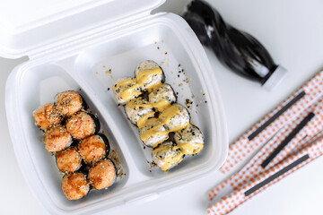 Hot baked rolls in a plastic box with soy sause and chopsticks (close up). Delivery service consept.