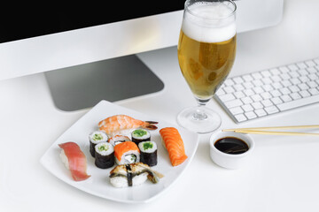 Assorted sushi and rolls near the computer. Eating at the workplace. Relax at home with a glass of...